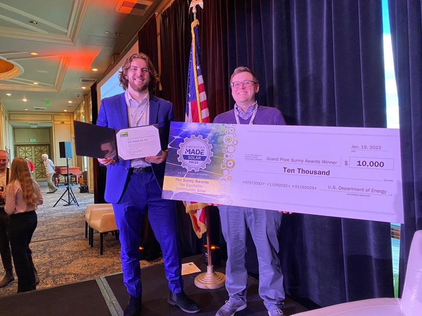 Two people holding grand prize check of $10,000 at Department of Energy Sunny Awards Conference 