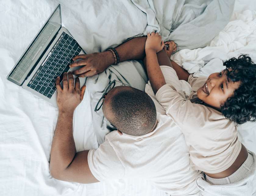 Father and daughter laying on the bed on laptop