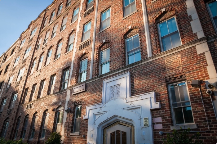 Façade of an older brick multifamily building in DC during the sunset.