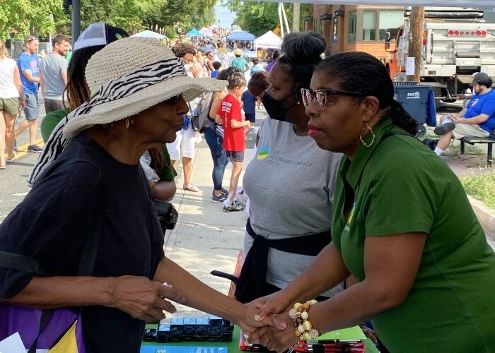 DCSEU staff member speaking to an elderly woman at a community event while holding hands.
