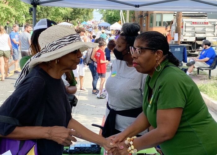 DCSEU staff member speaking to an elderly woman at a community event while holding hands.