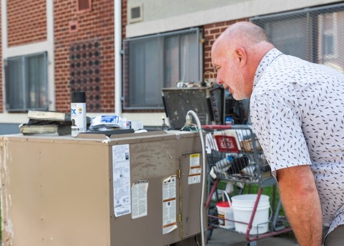 A property manager outside of a multifamily building reviewing recently uninstalled HVAC equipment.