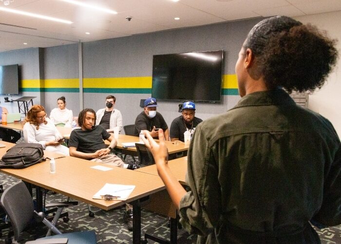 Instructor providing trainees with a presentation in an office setting while they listen.