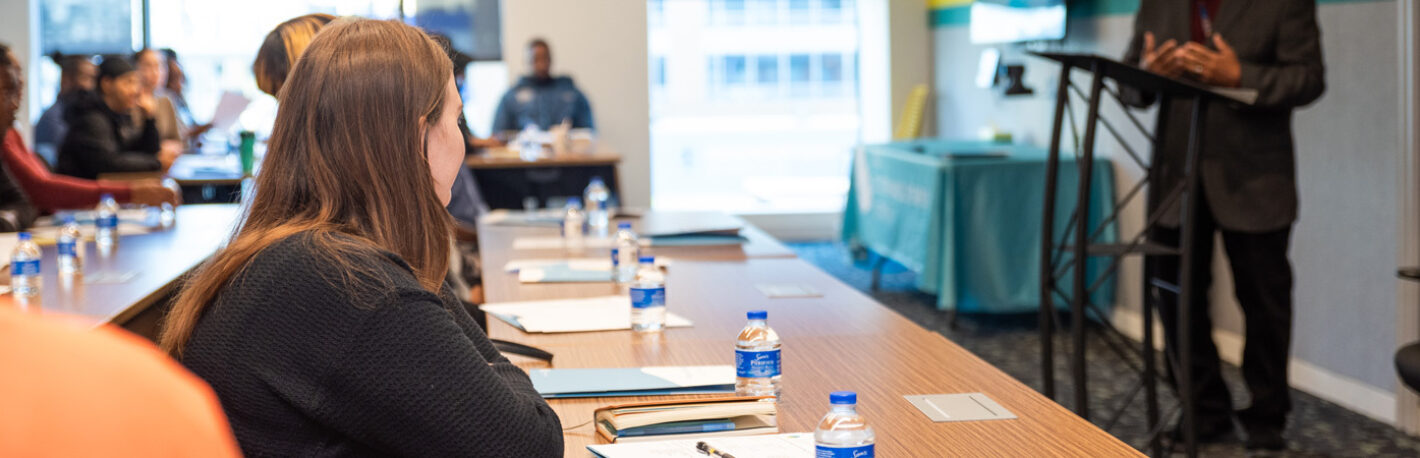 Young adult woman in the Workforce Development Program listening to a presentation from a guest speaker at the DCSEU offices.