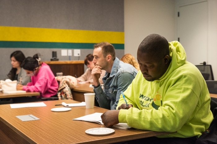 Row of students listening and taking notes in a classroom and office setting.