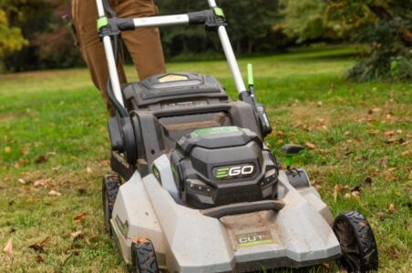 Close up of the front of an electric push lawn mower being operated.