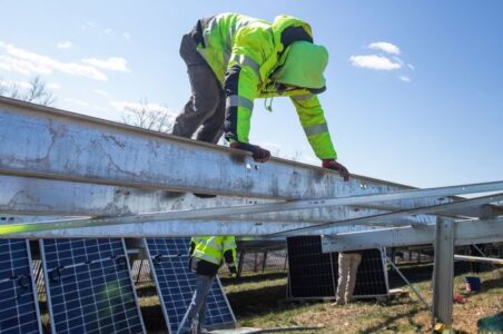 Solar installer climbing on bare ground-mounted solar array racking in preparation for an install.