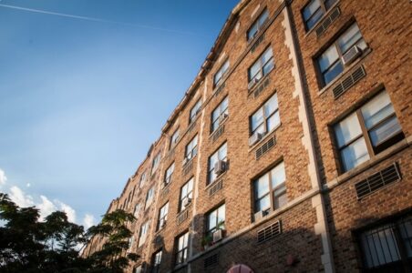 Façade of an older brick multifamily building in DC during the sunset.