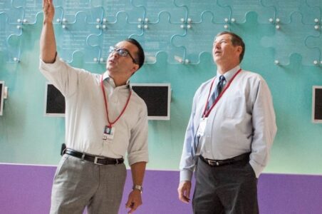 Two auditors looking up towards the ceiling of a commercial building and pointing.