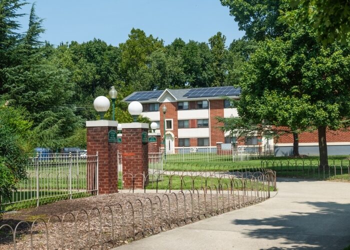 Affordable housing complex in Ward 7 with winding sidewalks, foliage, and rooftop solar panels.
