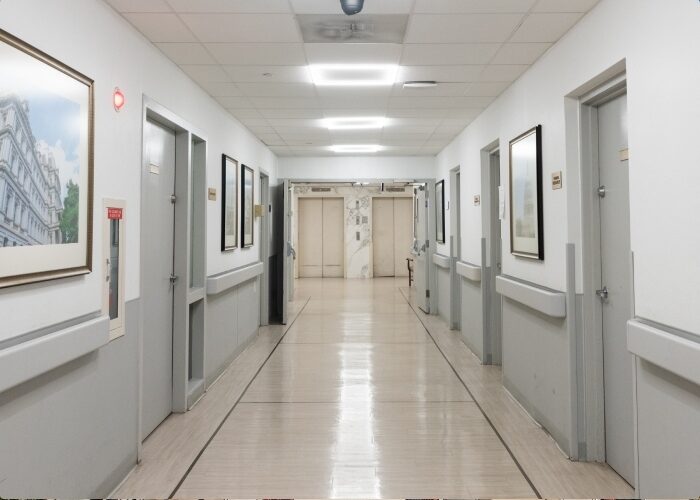 A well-lit white and gray hallway of a healthcare clinic with LED fixtures.