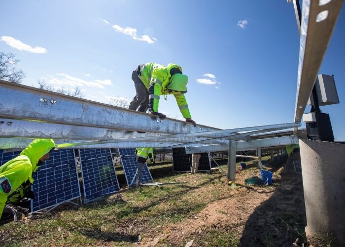 Solar installer climbing on bare ground-mounted solar array racking in preparation for an install at the Brentwood Reservoir CREF.