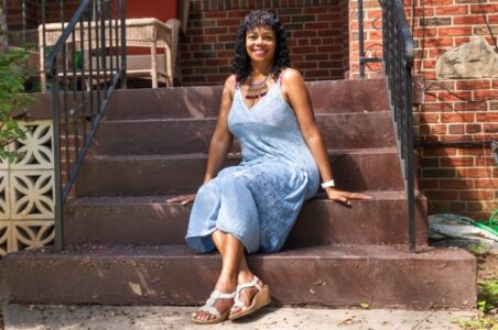 Ms. Senior DC 2023, Cerise Turner, a Solar for All and Affordable Home Electrification Program customer, sitting on the porch outside her home.
