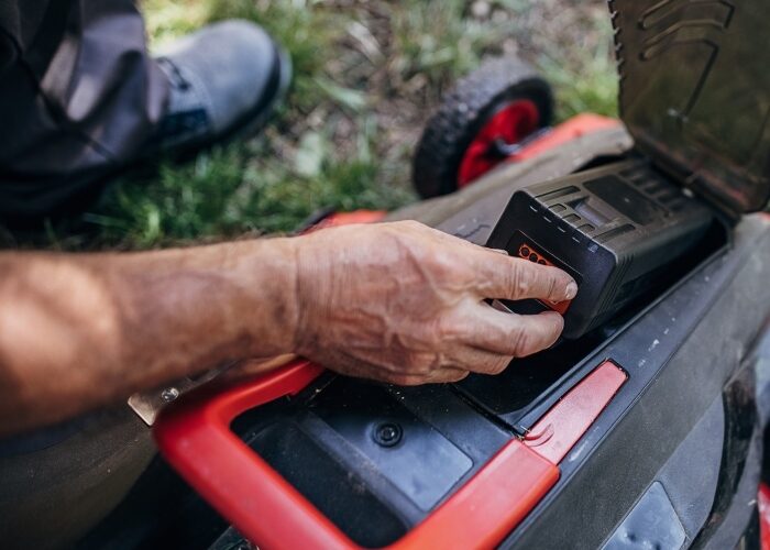 Closeup of a person inserting a battery into a commercial electric lawn mower.