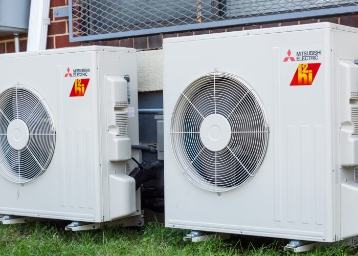 Closeup of two white mini split heat pump compressors.