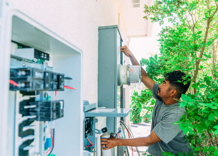 An electrician outside of a home upgrading the electric service panel to 200 amps, also know as a heavy-up.