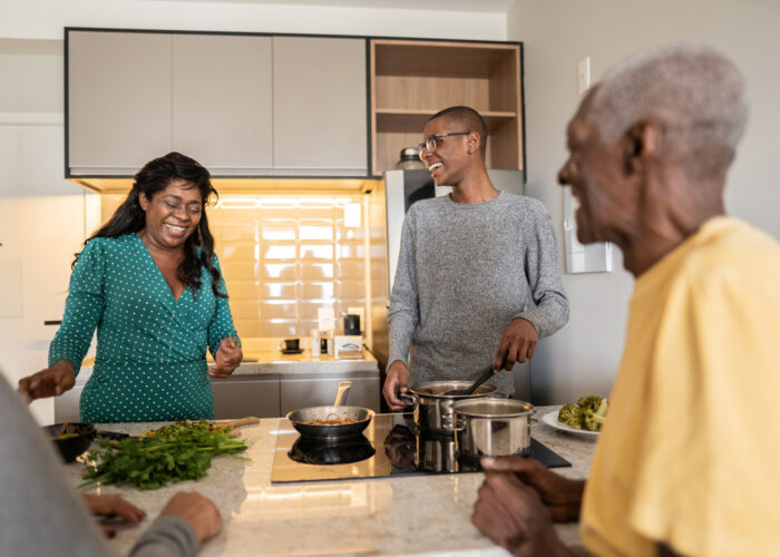 A family in the kitchen laughing and cooking around an induction stovetop.