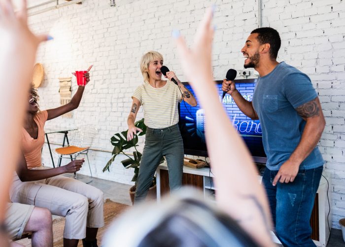 Group of young people singing in front of an ENERGY STAR certified television while playing a karaoke game on the tv.