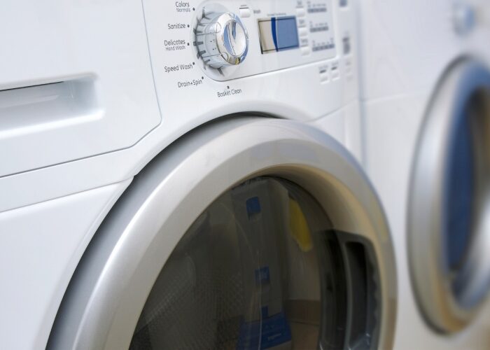 Close up of a white clothes washer with a dryer right beside it in the background.