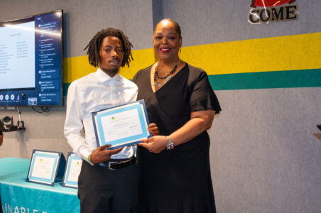 Workforce Development Program Manager, Gleniss Wade, posing with recently graduated extern, Dominique Johnson, holding his certificate of completion.