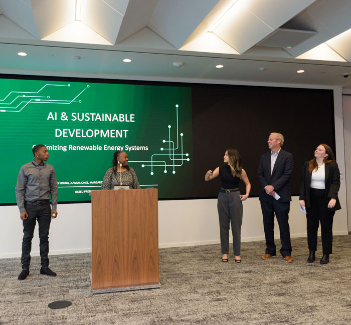 Five externs giving a presentation to graduation attendees on artificial intelligence and sustainable development.