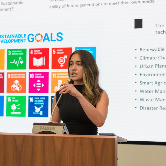 Ana Sanchez, extern at Greening Urban, giving a presentation in front of a colorful screen on renewable energy optimizing.