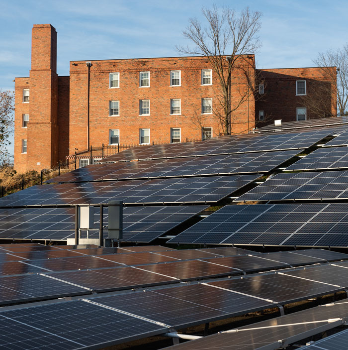 Ground mounted community solar system on an incline with a Fairfax Village Condominium building in the background.