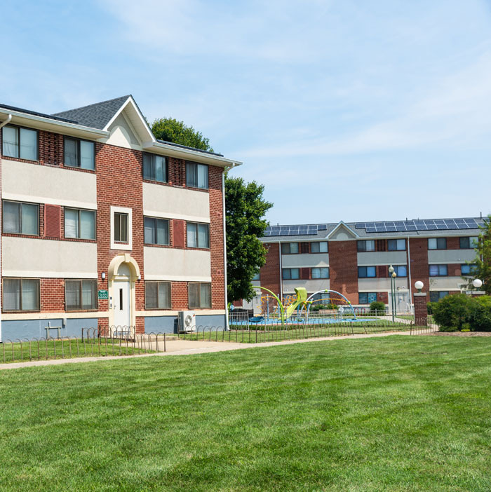 Paradise at Parkside apartment complex buildings and children's playground with a community solar array visible on the building in the background.