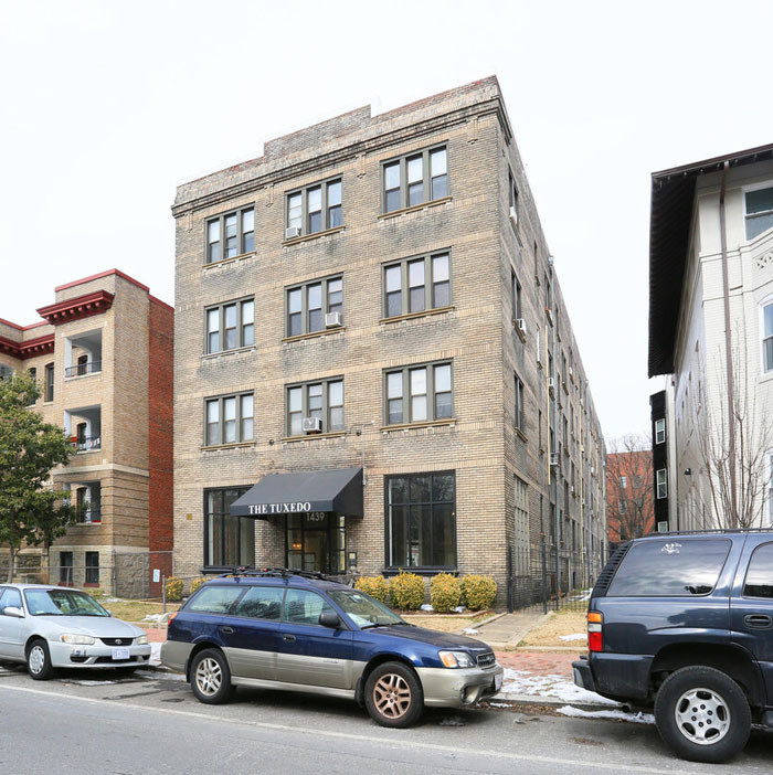 Street view of the Tuxedo on T Street building facade with cars parked in front of it.