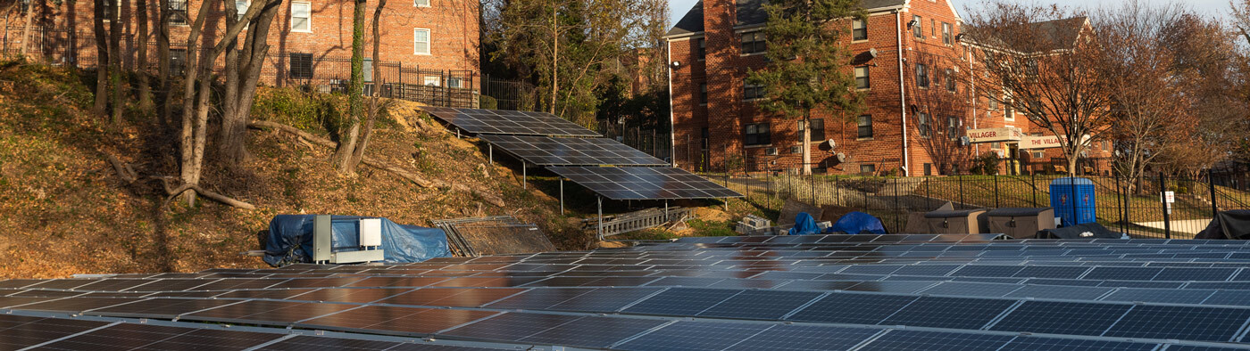 Large ground mounted community solar array on Fairfax Village Condominium land. Most of the panels are on flat ground with some on an incline.