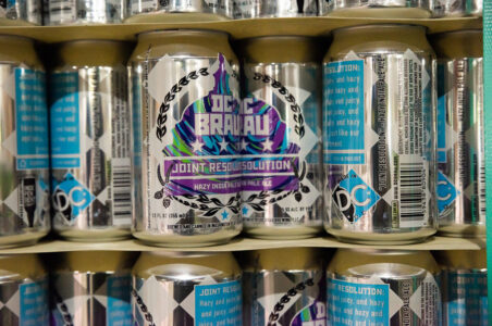 Closeup of the wall of silver, blue, and purple DC Brau beer cans.