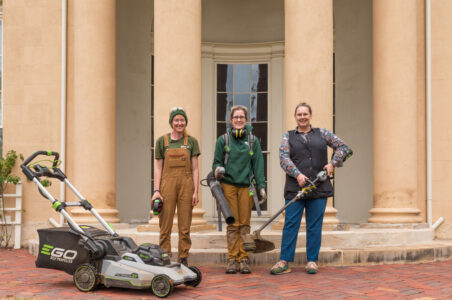 Three groundskeepers at the Historic Tudor Place and Gardens Estate pose with their new electric lawn mower, leaf blower, and string trimmer.