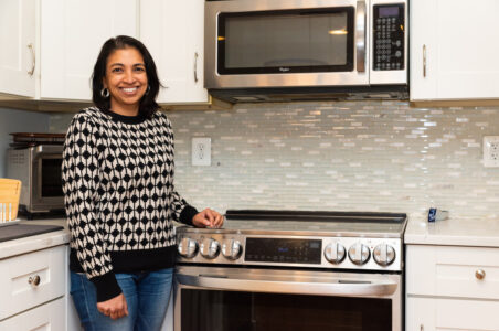 Parsa, a Ward 3 DC resident, standing in her kitchen next to her stainless-steel induction stove that she received a rebate on from the DCSEU.