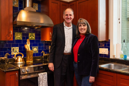 Dave and Carey, standing in their kitchen next to their new induction range hugging each other.