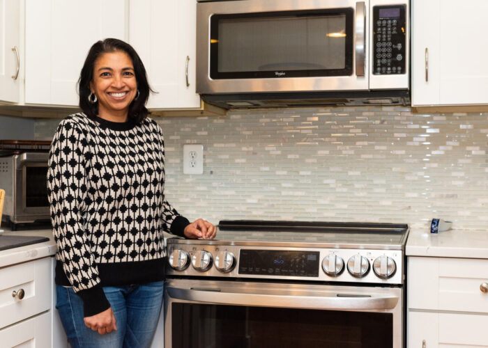 Parsa, a Ward 3 DC resident, standing in her kitchen next to her stainless-steel induction stove that she received a rebate on from the DCSEU.