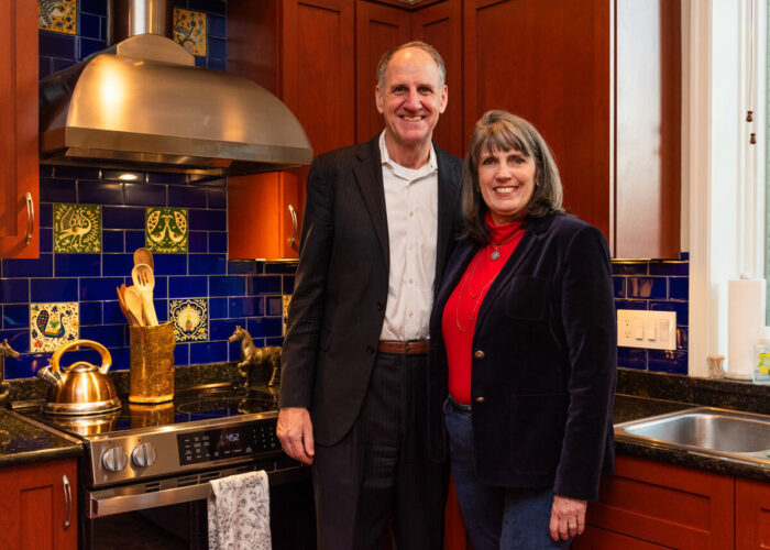 Dave and Carey, standing in their kitchen next to their new induction range hugging each other.