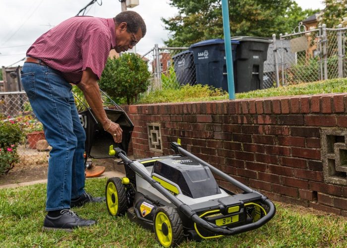 Mr. Woodfin, an African American District resident, changing the clippings bag on his electric lawn mower in his backyard.