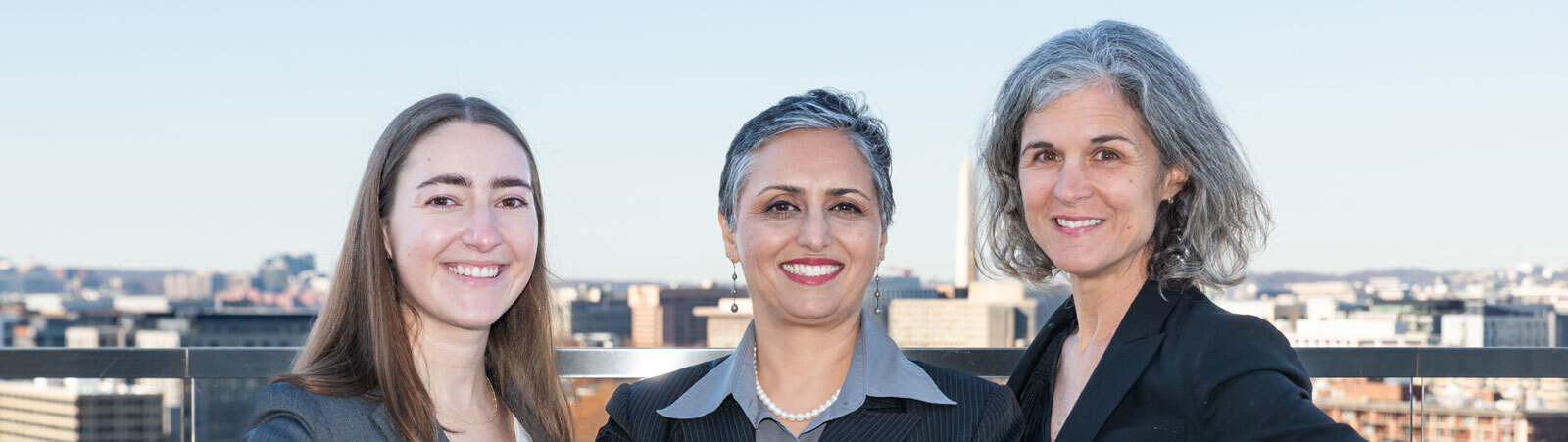 The women of Energy Shrink. Kara, Smita, and Christie posing in front of the DC skyline with the Washington Monument visible in the background.