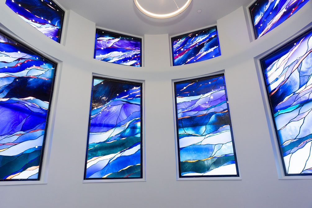 Curved and renovated chapel room at the Festival Center with abstract stain glass windows of multiple blue shades.