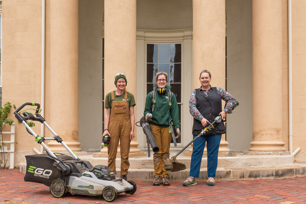 Three groundskeepers at the Historic Tudor Place and Gardens Estate pose with their new electric lawn mower, leaf blower, and string trimmer.