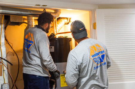 Two HVAC installers looking at a newly installed heat pump water heater.