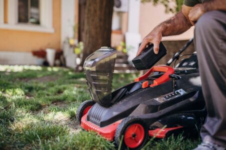 A person outside putting a battery in an electric lawn mower.