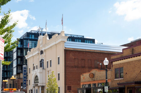 A view from the street on a sunny day of The Historic Howard Theatre facade where the theatre's new solar panels can be seen covering the entire roof.