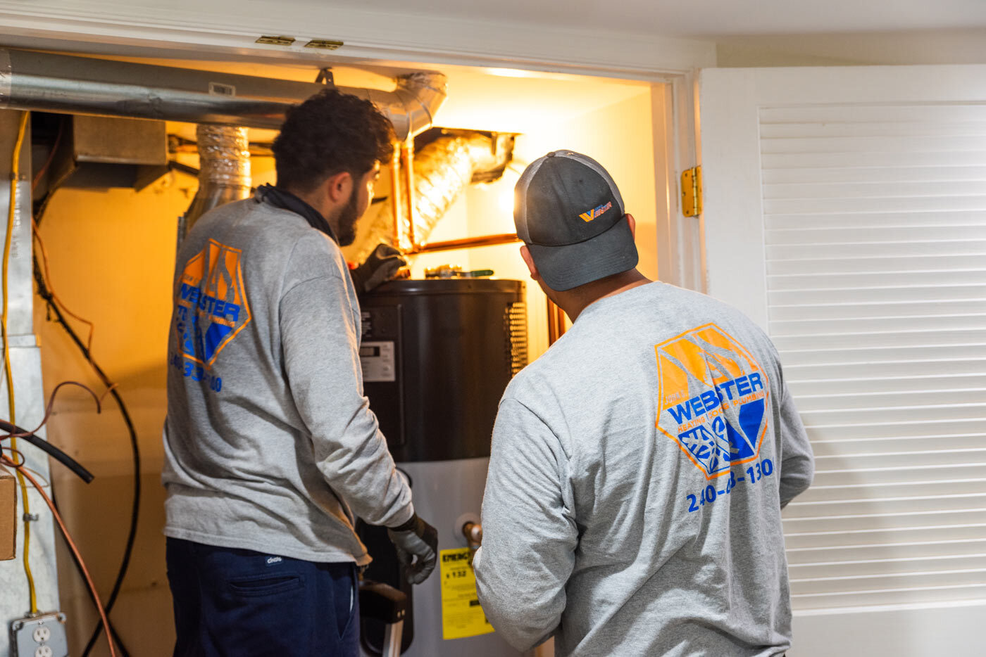 Two HVAC installers looking at a newly installed heat pump water heater.