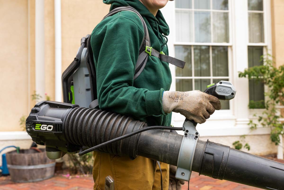 Close up of a lawn care worker wearing an electric backpack leaf blower.
