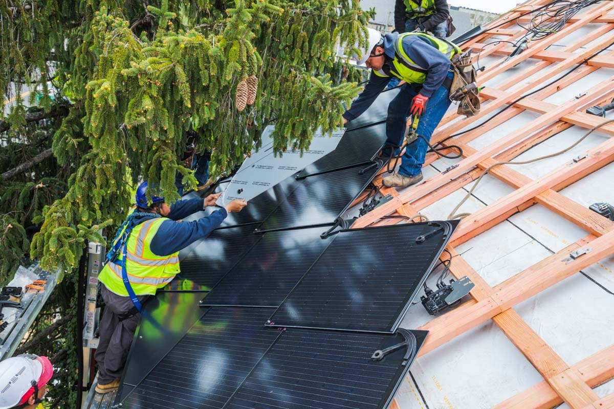 Contractors installing solar shingles on a roof.