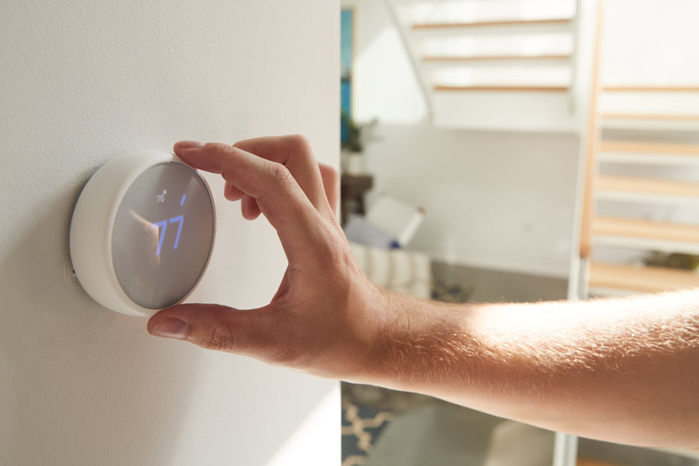 Close up of a hand adjusting a smart thermostat in a home.