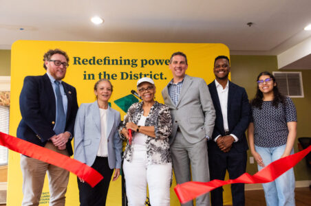 Project partners and a building resident cutting the ribbon at Victory Square Senior Apartments in front of a yellow backdrop. From left to right: Ben Burdick, DCSEU managing director, Leila A. Finucane, Victory Housing CEO, Linda Frazier, building resident, Nick Burger, DOEE deputy director, Jamal Lewis, SEUAB chair, Sidra Siddiqui, SEUAB member.