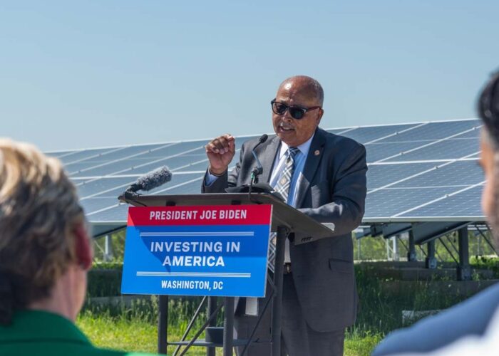 Ernest Jolly, providing remarks at an event in front of solar panels.