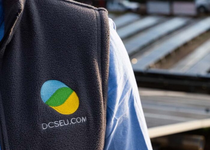 Close up of vest with DCSEU logo on it with community solar system visible in the background.